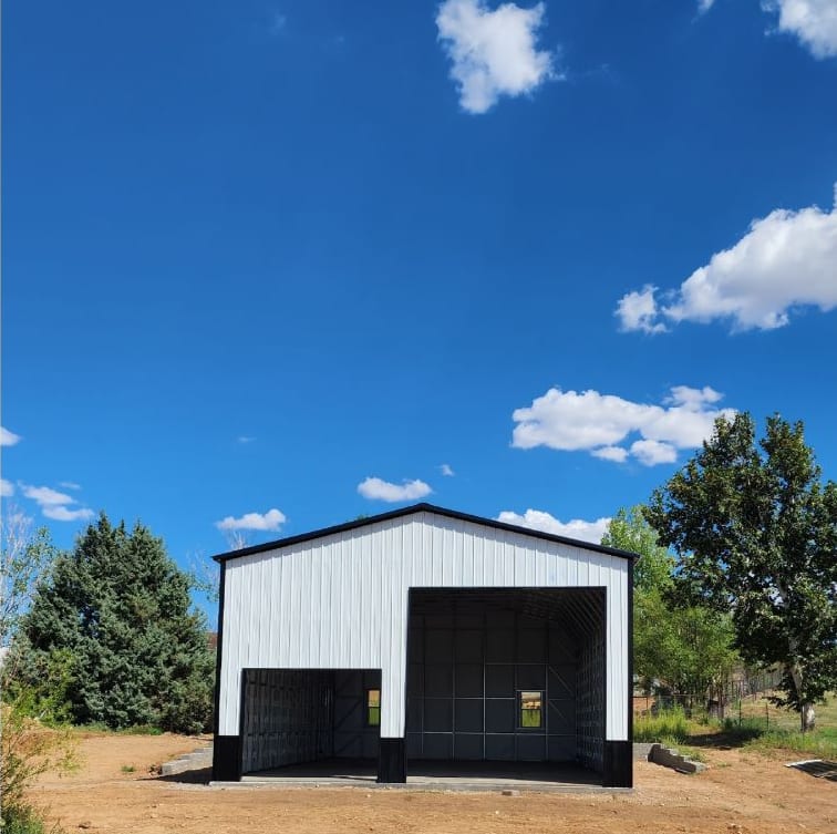 White metal garage with black trim and wainscot, one large and one smaller open bay