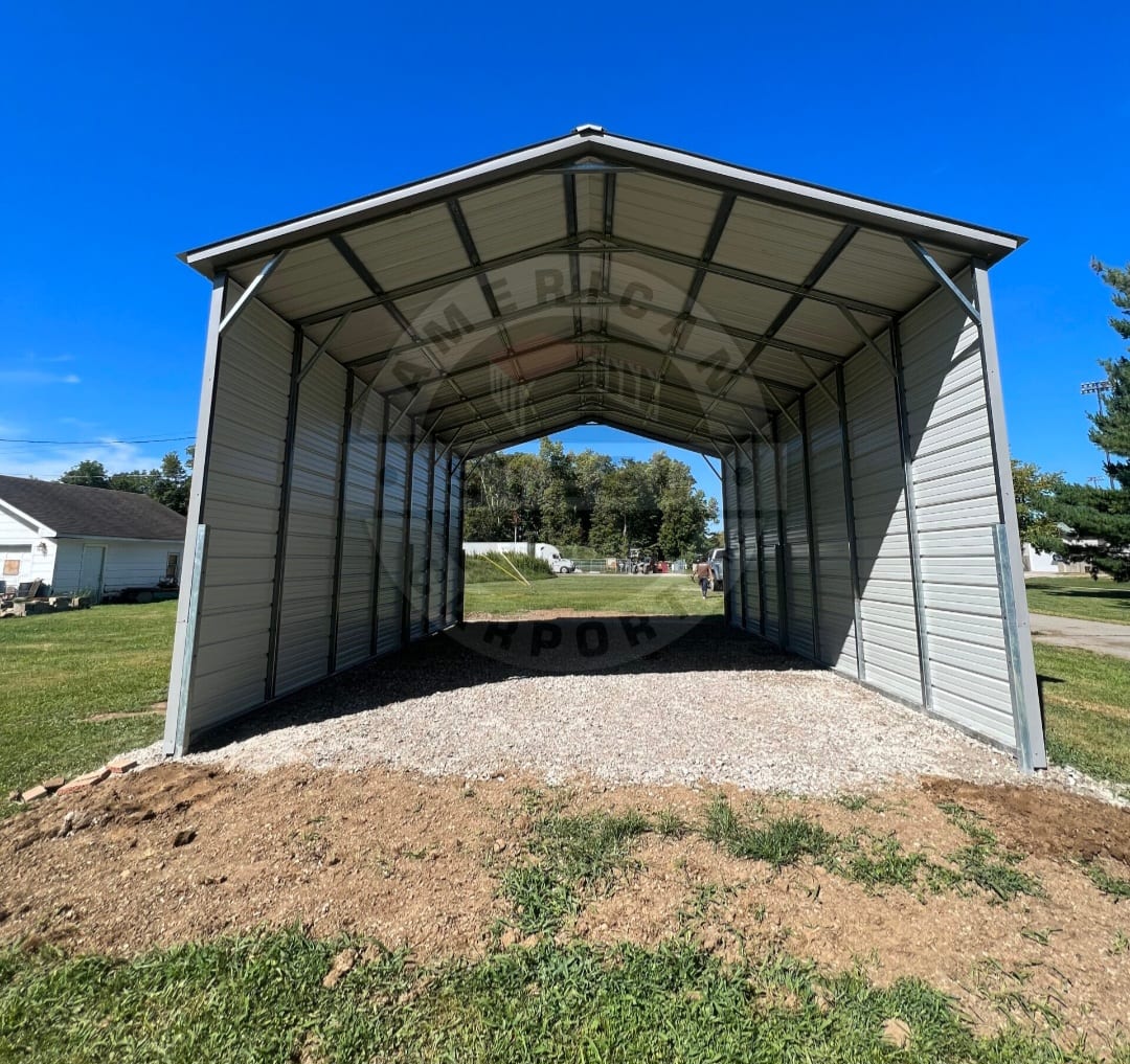 Metal carport with fully enclosed sides and open ends on a gravel pad